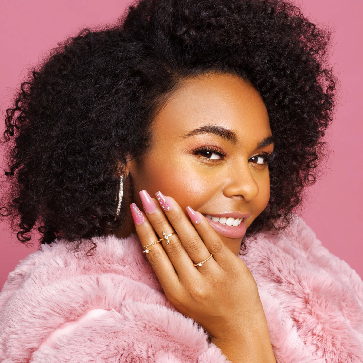 Mano modelando uñas KISS Be Jelly en gel rosa translúcido con efecto jelly, brillos y piedras decorativas